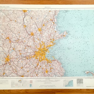 Può includere: Una mappa vintage di Boston, Massachusetts, che mostra strade, città e specchi d'acqua. La mappa è stampata su uno sfondo bianco con accenti blu, rossi e gialli. La mappa è intitolata "Boston" e include il testo "Eastern United States (Cropped)" nell'angolo in alto a sinistra.