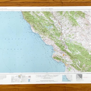 May include: A vintage topographic map of San Luis Obispo, California, showing the Pacific Ocean, coastline, and surrounding terrain. The map is printed on white paper with blue, green, and brown lines and text.