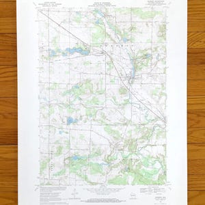 Può includere: Una mappa topografica dettagliata con curve di livello, corpi idrici e strade. Stampata su carta bianca, la mappa include testo che indica l'origine e la scala. La mappa è una rappresentazione dettagliata del terreno.