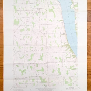 May include: A folded topographic map of the State of New York, featuring the Owasco Lake area. The map displays contour lines, green shaded areas, and text indicating geographical features and place names. The map is on a white background.