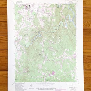 May include: A detailed topographic map with green, white, and pink hues, showing contour lines, roads, and water features. The map includes text indicating its origin from the U.S. Department of the Interior, Geological Survey.