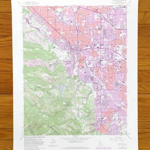 May include: A detailed topographic map of a suburban area, featuring a mix of green, pink, and purple hues. The map shows roads, buildings, and natural features, with text indicating the map's title and scale. The map is printed on white paper.