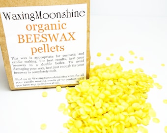 May include: A bag of organic beeswax pellets for candle making. The bag is brown with white text that reads "Waxing Moonshine organic BEESWAX pellets". The text also includes instructions for using the beeswax pellets. The bag is sitting on a white surface with a pile of yellow beeswax pellets in front of it.