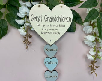 May include: A wooden heart-shaped sign with the text "Great Grandchildren" and the quote "Fill a place in your heart that you never knew was empty". Three smaller wooden hearts hang below the large heart, each with a name: Kyann, Callen, and Lucas.