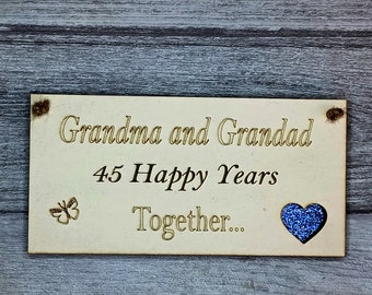 Może przedstawiać: Drewniany znak z tekstem "Grandma and Grandad 45 Happy Years Together..." z niebieskim sercem z brokatem i wyciętym motylem.