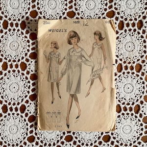May include: Vintage sewing pattern for a dress, size 12, Weigel's pattern number 2565. The pattern shows three women wearing the dress, which has a collar and a loose fit.