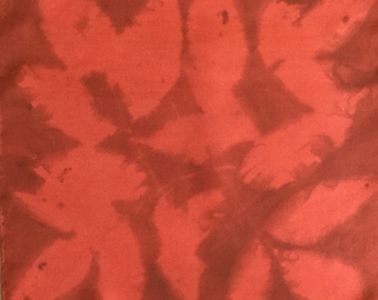Könnte beinhalten: Ein roter Seidenschal mit einem Batik-Muster aus braunen Blättern.