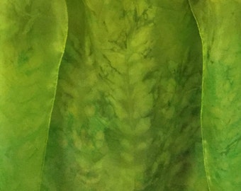 Könnte beinhalten: Ein grüner Seidenschal mit einem Batik-Muster. Der Schal ist in der Mitte gefaltet und hängt an einem Haken.