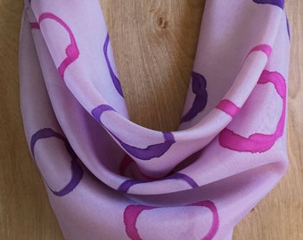 Könnte beinhalten: Ein helllila Seidentuch mit einem Muster aus rosa und violetten Kreisen.
