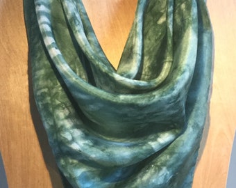 Könnte beinhalten: Ein grüner und weißer Seidenschal mit einem Batik-Muster. Der Schal ist über eine Holzpuppe gelegt.