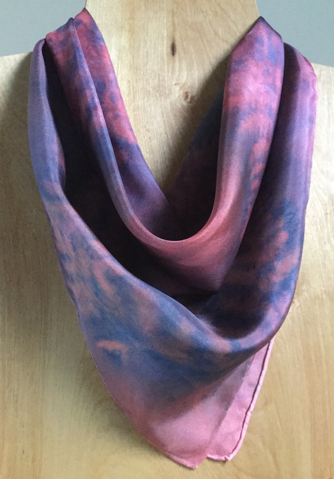 A hand-painted silk scarf featuring an eco fern print in shades of red, blue, and pink