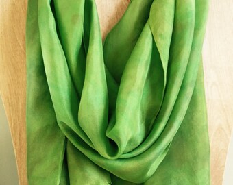 Könnte beinhalten: Ein weicher, grüner Seidenschal mit subtilem Ombre-Effekt. Der Schal ist über eine Holzpuppe gelegt.