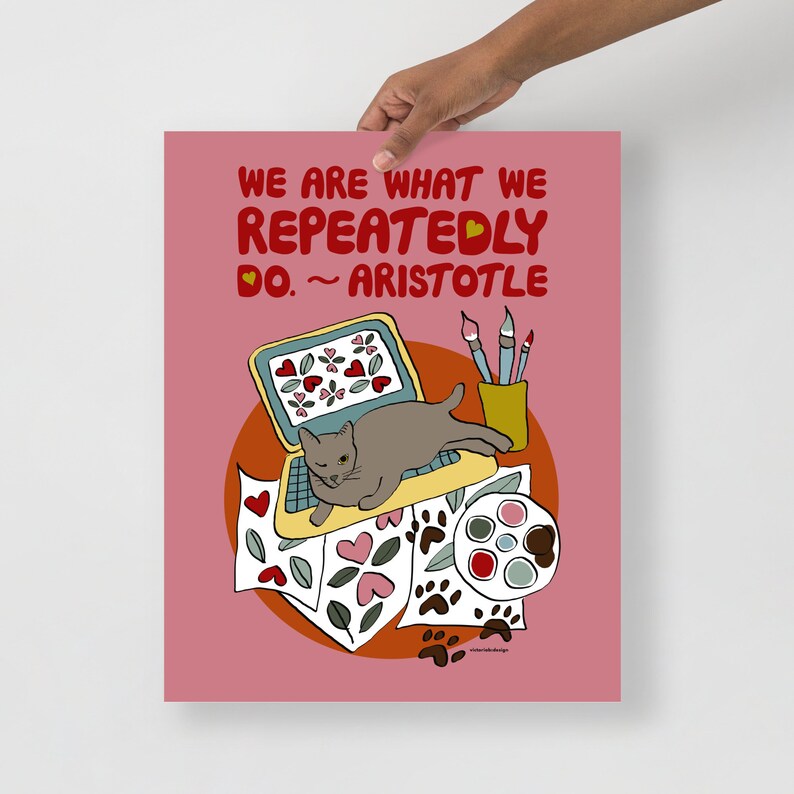 May include: A pink background with a quote in red text: "We are what we repeatedly do. ~ Aristotle".  A gray cat is sitting on a yellow laptop with a screen full of red hearts.  The laptop is on top of a pile of papers with hearts, paw prints, and leaves.  There is a yellow cup with paintbrushes and a paint palette with red, blue, and gray paint.