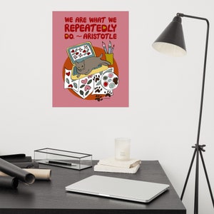 May include: A pink poster with a quote from Aristotle: "We are what we repeatedly do." The quote is illustrated with a cat sitting on a laptop surrounded by paintbrushes, paint, and paw prints.