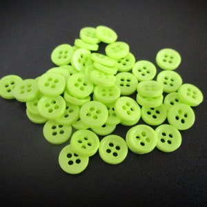 May include: A pile of bright green plastic buttons with four holes each.