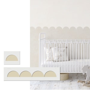 Könnte beinhalten: Ein weißes Babybett mit einem weißen Kissen mit goldfarbenem Muster und einem weißen Schaukelpferd. Die Wand hinter dem Babybett ist weiß gestrichen mit einem gewellten Rand in Cremefarbe. Der Text "Gute Nacht" steht auf dem Kissen.