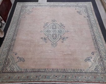 May include: A large, rectangular area rug with a central medallion design. The rug features a soft, muted color palette of peach, light blue, and navy. The border has a repeating geometric pattern. This rug is suitable for living rooms and bedrooms.