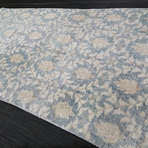 May include: A blue and beige patterned runner rug. The rug features a repeating floral and leaf design in beige against a blue background. The rug is rectangular and appears to be made of woven material.