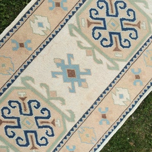 May include: A rectangular rug with a cream-colored central field and intricate geometric patterns. The border features a tan hue with blue, green, and brown accents. The rug's design includes stylized floral and geometric motifs, creating a traditional aesthetic.