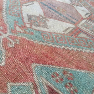 Puede incluir: Primer plano de una alfombra vintage con un patr&oacute;n geom&eacute;trico. La alfombra presenta una combinaci&oacute;n de colores, incluyendo rojo, turquesa y crema. El dise&ntilde;o incorpora formas de diamante y rectangulares.