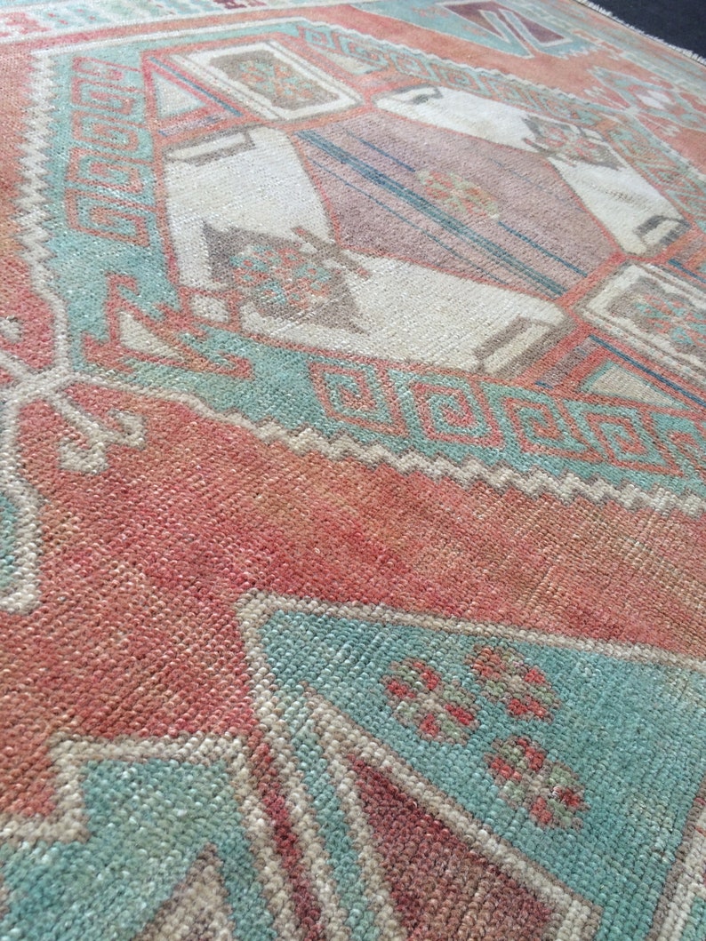 Puede incluir: Primer plano de una alfombra vintage con un patr&oacute;n geom&eacute;trico. La alfombra presenta una combinaci&oacute;n de colores, incluyendo rojo, turquesa y crema. El dise&ntilde;o incorpora formas de diamante y rectangulares.