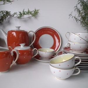 Könnte beinhalten: Ein Vintage-Tee-Set mit einem roten und weißen Tupfenmuster. Das Set enthält eine Teekanne, eine Milchkännchen, eine Zuckerdose, Tassen und Untertassen.