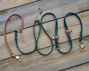 Puede incluir: Dos correas de cuero color turquesa para perros con herrajes de latón y una correa de cuero marrón con herrajes de latón.