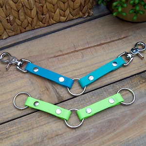 May include: Two dog leashes with metal rings and clips. One leash is teal blue and the other is lime green.