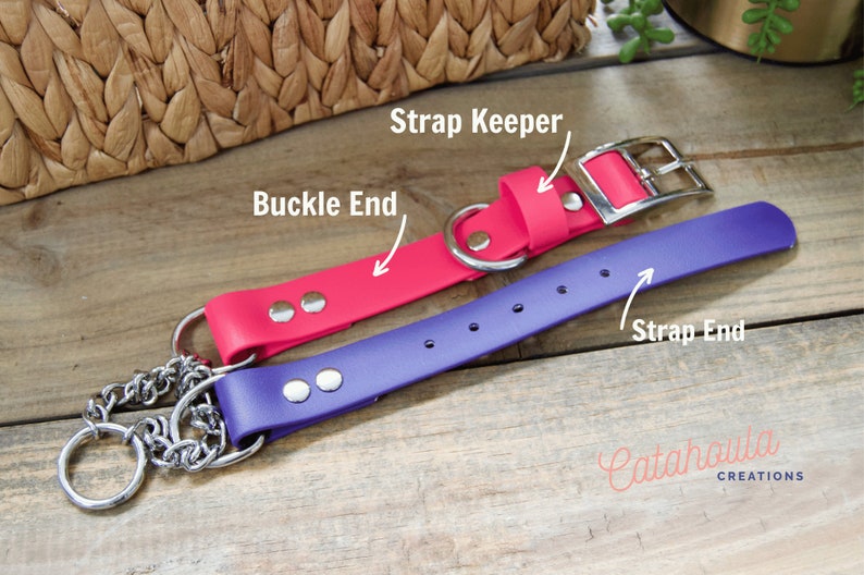 Pu&ograve; includere: Due collari per cani, uno rosa e uno viola, con accessori argentati. Il collare rosa ha una fibbia e un fermo per il cinturino. Il collare viola ha un'estremit&agrave; del cinturino e un attacco a catena. I collari sono su una superficie di legno.