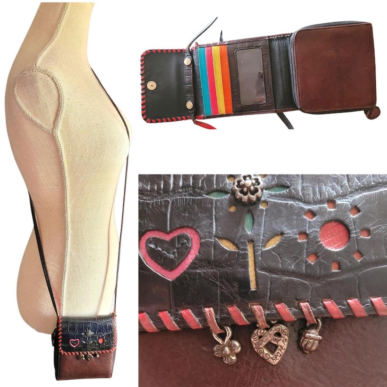 Puede incluir: Un bolso bandolera de cuero marr&oacute;n y negro con un dise&ntilde;o decorativo de coraz&oacute;n y flores. El bolso tiene una forma peque&ntilde;a y rectangular con una correa larga. La imagen tambi&eacute;n muestra una cartera a juego con ranuras para tarjetas coloridas y cierre de cremallera.