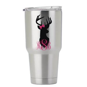 May include: Stainless steel tumbler with a black silhouette of a deer head with a pink bow and the monogram "KSB" in pink.