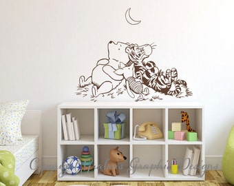 May include: A Winnie the Pooh wall decal featuring Winnie the Pooh, Piglet, and Tigger lying down and looking up at a crescent moon. The decal is brown and is on a white wall.