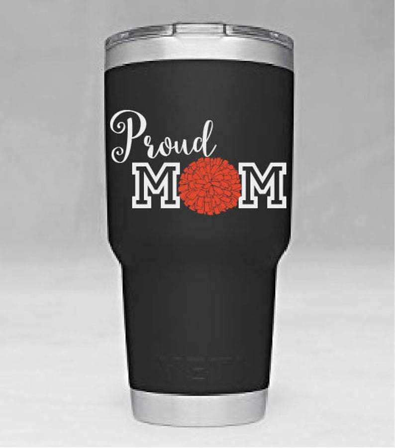 May include: Black stainless steel tumbler with a white design that says "Proud Mom" with a red pom-pom in the middle of the word "Mom".