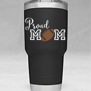 May include: Black stainless steel tumbler with a white design that says "Proud Mom" with a football graphic.