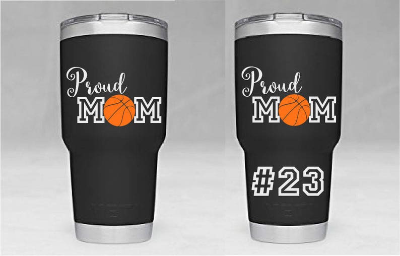 May include: Two black stainless steel tumblers with a white design that says "Proud Mom" with a basketball graphic. One tumbler has the number "23" on the bottom.