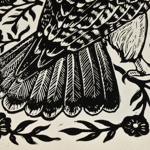 May include: Black and white linocut print featuring a bird's wing and tail feathers, surrounded by floral and leaf motifs. The artwork showcases detailed linework and a high-contrast design, suitable for wall decor.