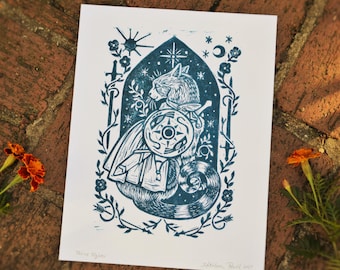 May include: A teal and white print of a cat warrior with a shield, sword, and cape, set within an arched frame with floral and celestial elements. The artwork is signed and titled "Fine Fighter."
