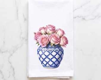 Könnte beinhalten: Ein weißes rechteckiges Küchentuch mit einer zentralen Abbildung eines Straußes aus zartrosa Rosen, der in einer abgerundeten blau-weißen Keramikvase mit einem sich wiederholenden geometrischen Gittermuster auf der gesamten Oberfläche steht.