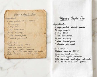 May include: A rectangular, aged, tan paper recipe card for Mom's Apple Pie next to a white kitchen towel featuring the same recipe printed in black cursive text. The recipe lists ingredients like apples, sugar, flour, cinnamon, nutmeg, lemon juice, and pie crust, with instructions to bake at 375 degrees Fahrenheit for 45 to 50 minutes.