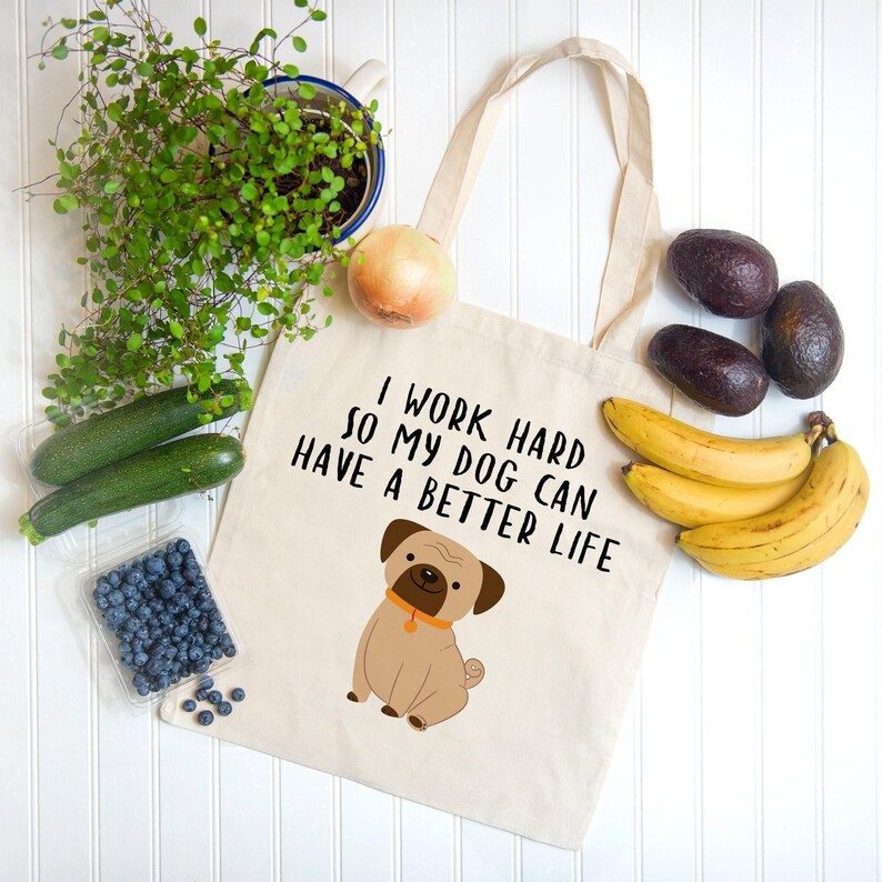 Dog tote bag arranged with bananas, avocados, blueberries, zucchini, an onion, and a potted plant.