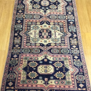 May include: A traditional Persian rug with a navy blue background and intricate geometric patterns in shades of pink, beige, and blue. The rug features a central medallion and repeating border designs.