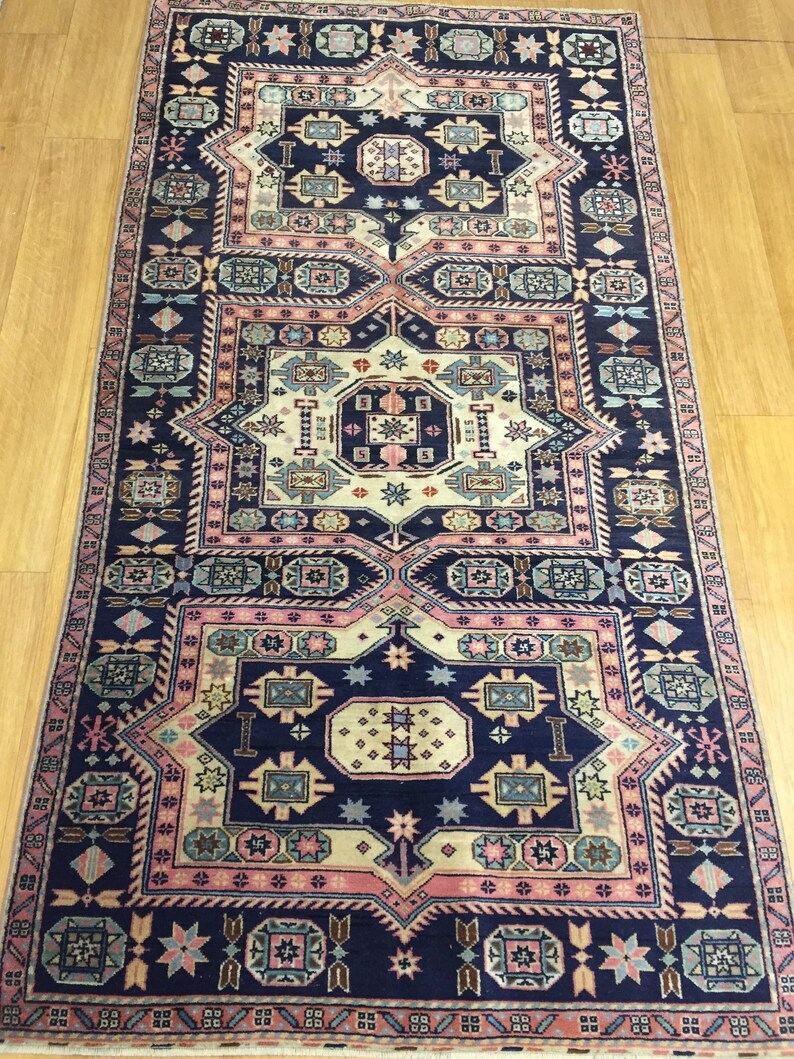May include: A traditional Persian rug with a navy blue background and intricate geometric patterns in shades of pink, beige, and blue. The rug features a central medallion and repeating border designs.