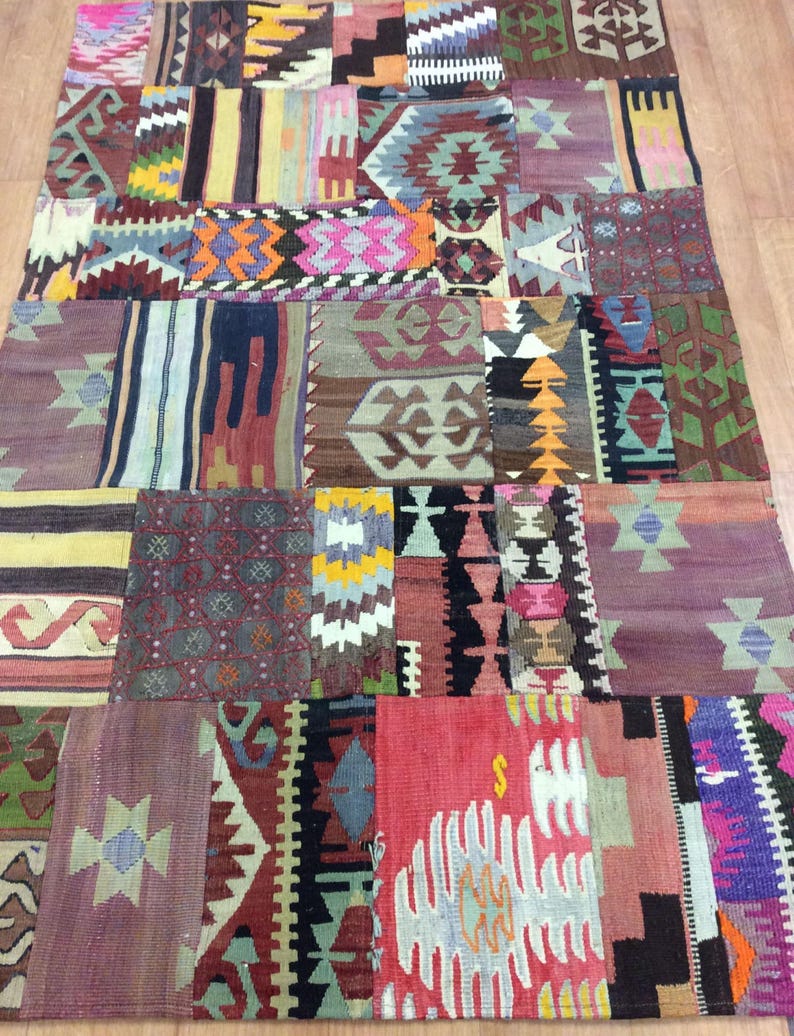 May include: A colorful patchwork rug with a variety of geometric patterns in shades of red, blue, green, yellow, and brown. The rug is made of wool and has a hand-woven texture.