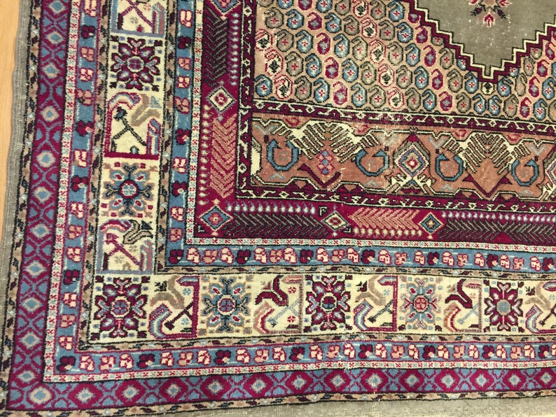 May include: Close-up of a colorful rug with intricate patterns in shades of blue, red, and beige. The rug has a traditional design with geometric shapes and floral motifs.