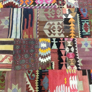 May include: A colorful patchwork rug with a variety of geometric patterns in shades of red, blue, green, yellow, and brown. The rug is made of woven fabric and has a traditional design.