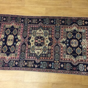 May include: A traditional Persian rug with a navy blue background and intricate geometric patterns in shades of pink, beige, and blue.