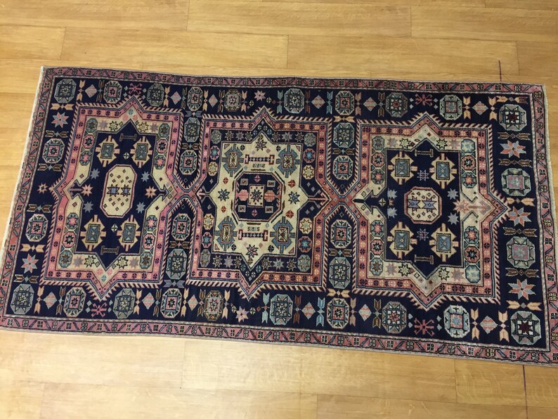 May include: A traditional Persian rug with a navy blue background and intricate geometric patterns in shades of pink, beige, and blue.