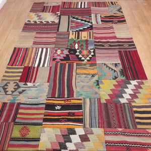 Op de afbeelding: Een kleurrijk patchwork tapijt met verschillende geometrische patronen in tinten rood, blauw, groen, geel en bruin.