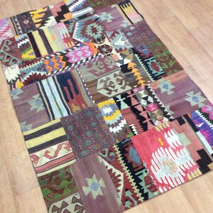 May include: A colorful patchwork rug with a variety of geometric patterns in shades of red, blue, green, yellow, and brown. The rug is made of woven fabric and has a fringed edge.