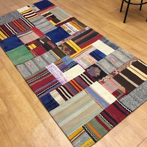 May include: A colorful patchwork rug made of different fabrics and patterns. The rug is rectangular and has a variety of colors, including red, blue, green, yellow, and brown.